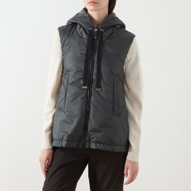 Model wearing Max Mara Cube green quilted hooded gilet, styled with a cream knit jumper and dark trousers.