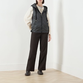 Model wearing Max Mara Cube green quilted gilet with hood, styled with cream knit, dark wide-leg trousers and black shoes