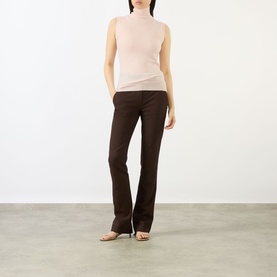 Model wearing Max Mara Sportmax pink sleeveless turtleneck knit top, styled with dark brown flared trousers and nude heeled mules.