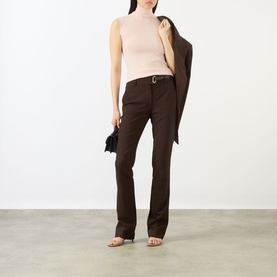 Model wearing Max Mara Sportmax pink sleeveless roll-neck knit top, styled with dark brown tailored trousers and a blazer draped over one shoulder.