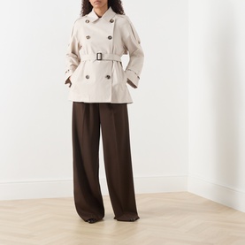 Model wearing Max Mara Cube silver cotton raincoat with double-breasted buttons and belt, styled with wide-leg brown trousers