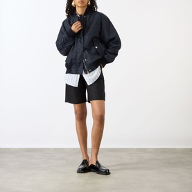 Model wearing Max Mara Sportmax Midnight Blue raincoat styled with a striped shirt, black shorts and black loafers