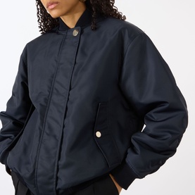Model wearing Max Mara Sportmax Midnight Blue polyamide raincoat with snap collar, gold-tone buttons, and oversized silhouette.