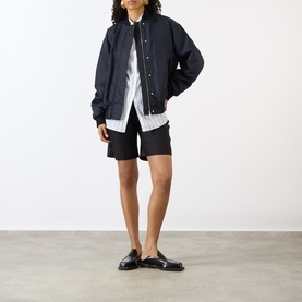 Model wearing Max Mara Sportmax Midnight Blue raincoat with white shirt, black shorts and black loafer mules.