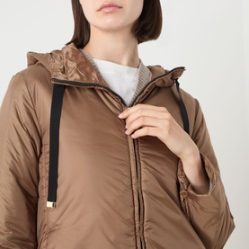 Model wearing Max Mara Cube honey quilted hooded jacket with zip fastening and gold-toned hardware detail, styled with a white top.