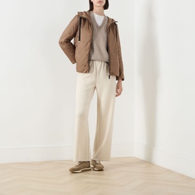 Model wearing Max Mara Cube honey quilted hooded jacket with grey knit, cream wide-leg trousers and brown trainers.