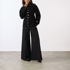 Model wearing Max Mara Sportmax Arena Button-Down Short Coat in black with wide-leg black trousers and black heels.