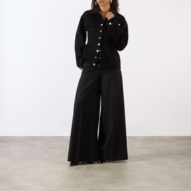 Model wearing Max Mara Sportmax Arena Button-Down Short Coat in black wool with silver buttons, styled with wide-leg black trousers.