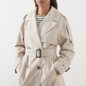 Model wearing Max Mara Cube Coro Trench Coat in silver, double-breasted with wide lapel, buckle belt and raglan sleeves, styled with a striped top.