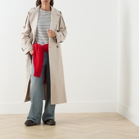 Model wearing Max Mara Cube Coro Trench Coat in silver, double-breasted with belt, styled with striped top, wide-leg jeans and red knitwear tied at