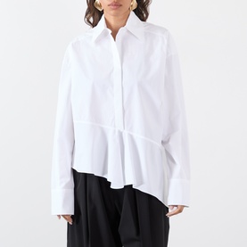 Model wearing Max Mara Sportmax Arcella Asymmetric Shirt in Optical White with flounce hem, styled with black wide-leg trousers.