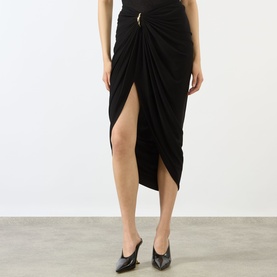 Model wearing Max Mara Sportmax black draped wrap midi skirt with gold-tone ring detail and thigh-high split, styled with black mules.