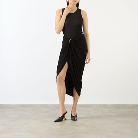 Model wearing Max Mara Sportmax black draped wrap midi skirt with front split, styled with black sleeveless top and heeled mules.