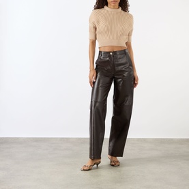 Model wearing Max Mara Sportmax beige ribbed crop top with mock neck, styled with dark brown leather trousers and strappy heeled mules.