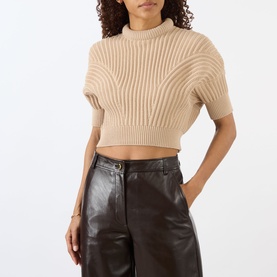 Model wearing Max Mara Sportmax beige ribbed cropped mock-neck knit top with short sleeves, styled with dark brown leather trousers.