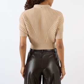 Model wearing Max Mara Sportmax beige ribbed knit short-sleeve top, back view, styled with dark leather trousers.