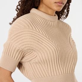 Model wearing Max Mara Sportmax beige chunky-knit short-sleeve top with ribbed texture and mock neck, close-up detail shot.