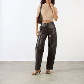 Model wearing Max Mara Sportmax beige knit crop top with puff sleeves, styled with dark brown leather wide-leg trousers and strappy heels.