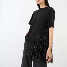 Model wearing Max Mara Sportmax nero cotton T-shirt with diagonal black fringe trim, styled with dark wide-leg trousers.
