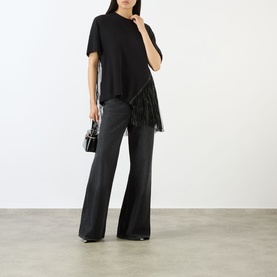 Model wearing Max Mara Sportmax Nero cotton top with fringe trim, styled with dark wide-leg trousers and small black bag.