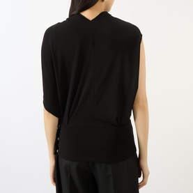 Model wearing Max Mara Sportmax black sleeveless top, rear view showing relaxed drape, V-back neckline, and side button detail with wide-leg trousers.