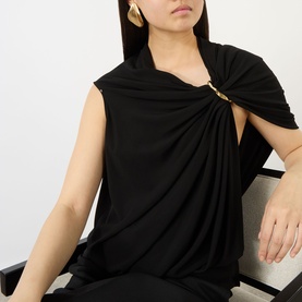 Model wearing Max Mara Sportmax black draped top with gold pin detail, styled with gold drop earrings