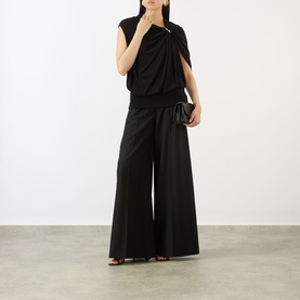 Model wearing Max Mara Sportmax black draped viscose top with asymmetric neckline, styled with wide-leg black trousers and dark clutch bag.