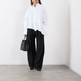 Model wearing Max Mara Sportmax Zorro Wide-Leg Trousers in black wool, styled with a white oversized shirt and black heels. Model carries a black