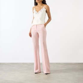 Model wearing Max Mara Sportmax Antique Rose flared wool trousers, styled with a white lace-trim camisole top.