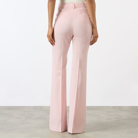 Model wearing Max Mara Sportmax Antique Rose wide-leg wool trousers, back view, with high-rise waistband and flared hem