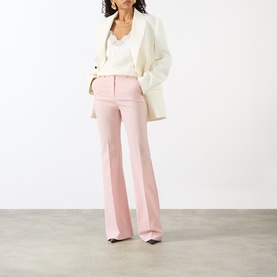 Model wearing Max Mara Sportmax Antique Rose flared wool trousers, styled with a white blazer and white camisole top.