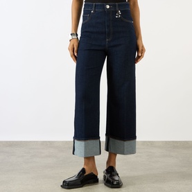 Model wearing Max Mara Sportmax Ultramarine wide-leg denim trousers with deep turn-up cuffs, styled with black loafers.