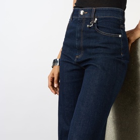 Model wearing Max Mara Sportmax ultramarine denim trousers, high-waist fit with silver button detail, styled with a black top and grey watch.