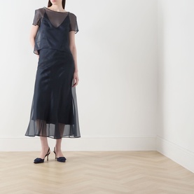 Model wearing Piano Forte Astrale Organza Skirt in Midnight Blue, midi length, styled with matching sheer top and kitten heel pumps.