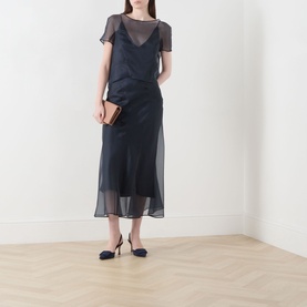 Model wearing Piano Forte Mela Organza Top in Midnight Blue with slip dress layer, styled with navy heels and a tan clutch bag.