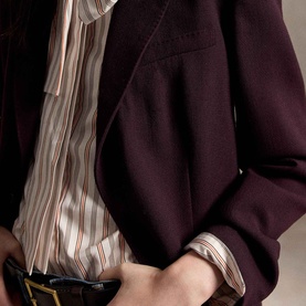 Model wearing Polo Ralph Lauren Midnight Merlot blazer, styled with a pink stripe shirt and black leather belt with gold buckle.