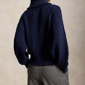 Model wearing Polo Ralph Lauren Hunter Navy cable-knit turtleneck cardigan, back view, styled with grey trousers