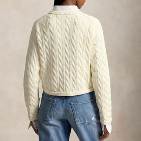 Model wearing Polo Ralph Lauren Clubhouse Cream cable-knit cardigan, back view, styled with blue distressed jeans.