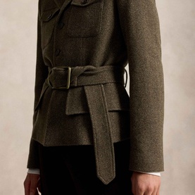 Model wearing Polo Ralph Lauren Belted Tweed Utility Jacket in Loden Herringbone, showing gold-tone buckle belt detail, styled with white shirt and