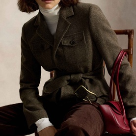 Model wearing Polo Ralph Lauren Belted Tweed Utility Jacket in Loden Herringbone with gold-tone buckle belt, styled with white turtleneck and brown