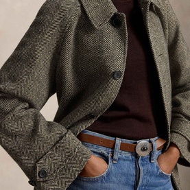 Model wearing Polo Ralph Lauren Black/Cream Herringbone Coat, styled with a burgundy knit, blue jeans and brown leather belt.