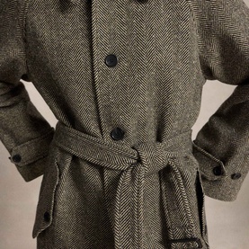 Model wearing Polo Ralph Lauren Black/Cream Herringbone Coat, featuring button front, tie belt at waist and cuffed sleeves.