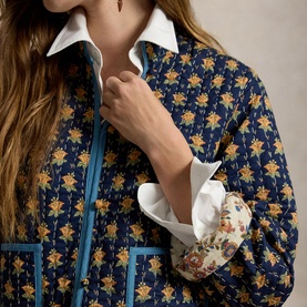 Model wearing Polo Ralph Lauren Navy Multi floral quilted jacket with blue trim, styled with white collared shirt and floral cuff detail