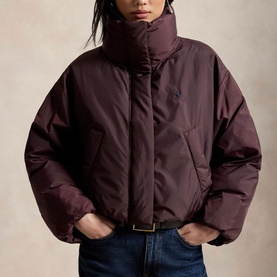 Model wearing Polo Ralph Lauren Dark Shadow Burgundy puffer coat with high funnel neck, styled with blue jeans and brown belt.