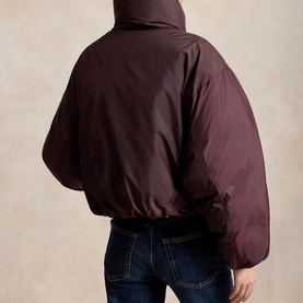 Model wearing Polo Ralph Lauren Dark Shadow Burgundy cropped puffer coat, back view, styled with dark blue jeans.