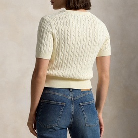 Model wearing Polo Ralph Lauren Clubhouse Cream cable-knit short-sleeve sweater, styled with blue denim jeans, seen from the back.