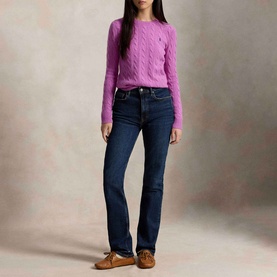 Model wearing Polo Ralph Lauren Pony Logo Cable Knitted Sweater in Thistle Pink with dark wash bootcut jeans and tan loafers.
