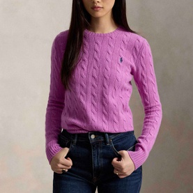 Model wearing Polo Ralph Lauren Pony Logo Cable Knitted Sweater in Thistle Pink with crew neck, styled with dark blue jeans.