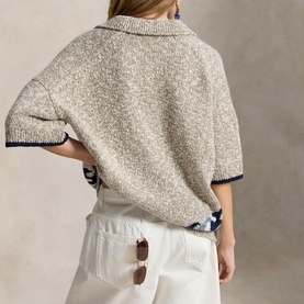 Model wearing Polo Ralph Lauren cream knit short-sleeve polo sweater with navy trim, styled with white trousers, back view.