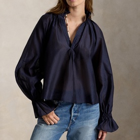 Model wearing Polo Ralph Lauren Hunter Navy shirt with gathered V-neckline, voluminous sleeves and ruched cuffs, styled with light-wash jeans